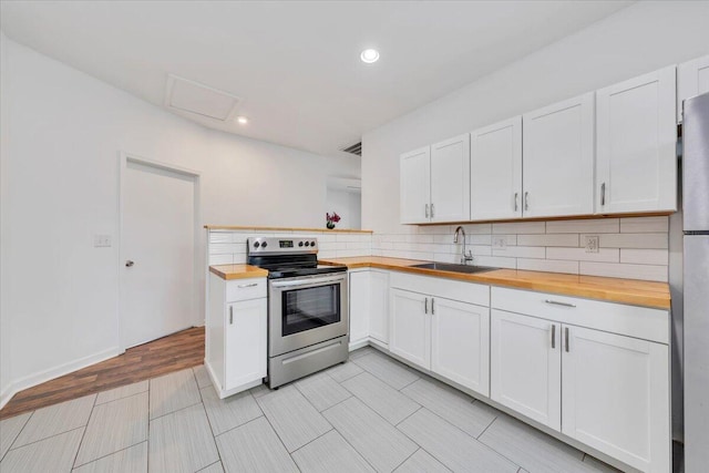 1113 17th St SE, Roanoke, VA 24013 - kitchen with white cabinets, appliances with stainless steel finishes, a sink, butcher block countertops, and backsplash