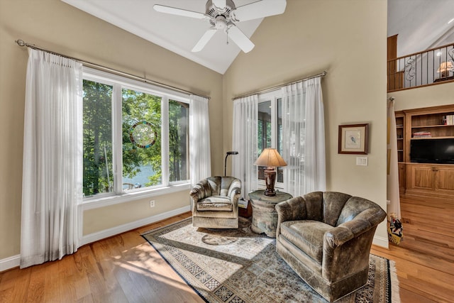 sitting room with a ceiling fan, high vaulted ceiling, baseboards, and light wood-type flooring