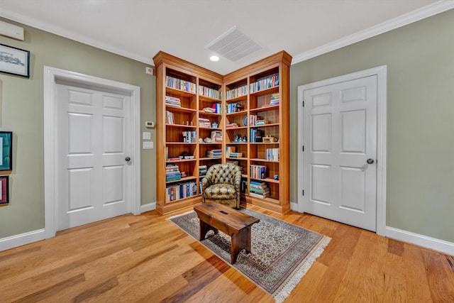 living area featuring baseboards, visible vents, ornamental molding, and wood finished floors