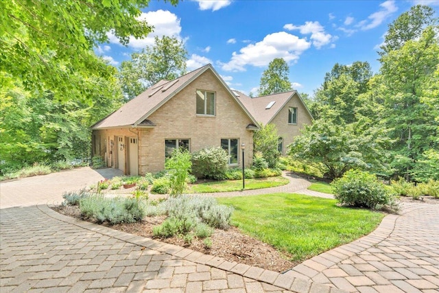 view of front of house with brick siding, decorative driveway, a garage, and a front lawn