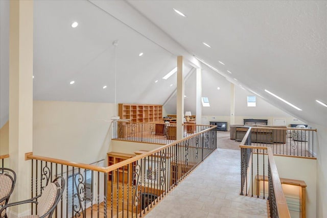 hall featuring an upstairs landing and lofted ceiling with skylight