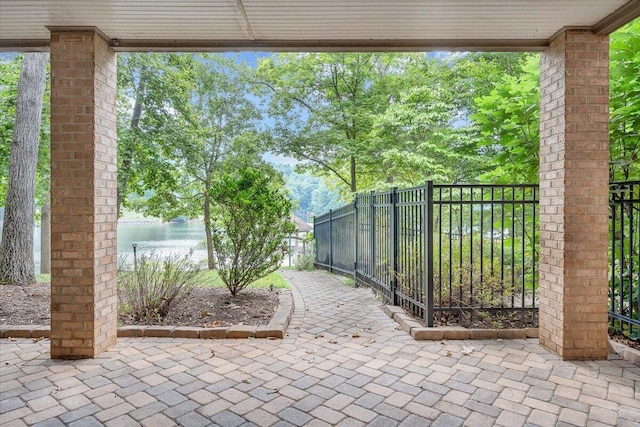 view of patio featuring a water view and fence