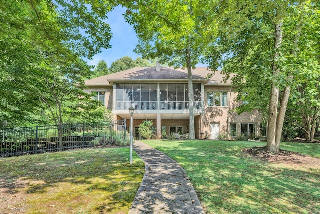 back of property featuring a lawn, a sunroom, and fence