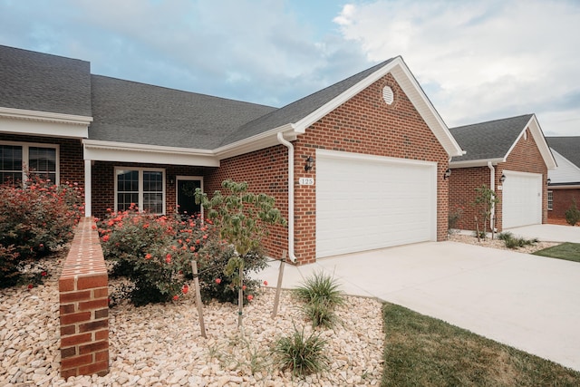 ranch-style home featuring a shingled roof, a garage, brick siding, and concrete driveway