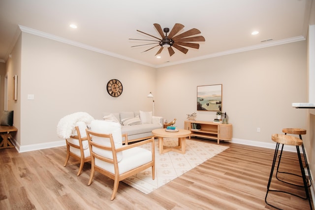 living room with ornamental molding, baseboards, light wood-style floors, visible vents, and ceiling fan
