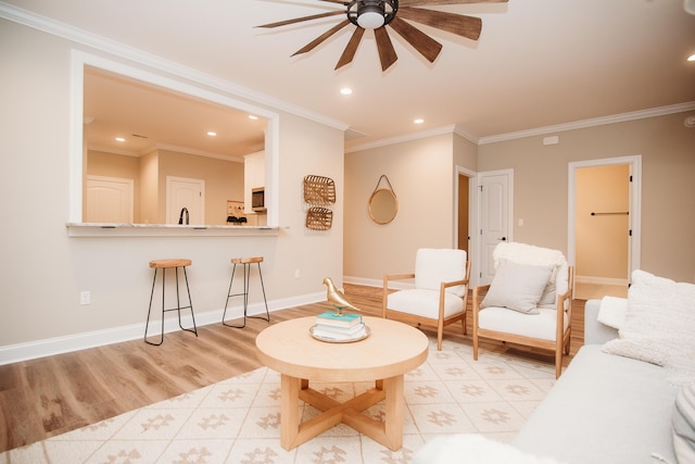 living room featuring baseboards, crown molding, light wood-style flooring, and a ceiling fan