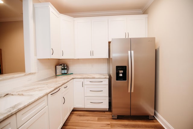 kitchen featuring crown molding, light wood finished floors, stainless steel fridge with ice dispenser, white cabinets, and decorative backsplash