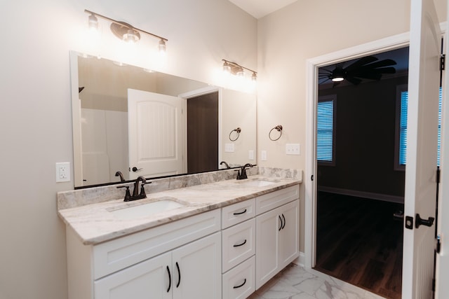 bathroom featuring baseboards, marble finish floor, a sink, and double vanity