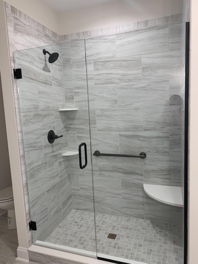full bath featuring a stall shower and toilet