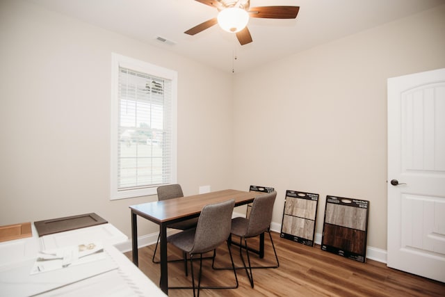 dining space with baseboards, visible vents, a ceiling fan, and wood finished floors