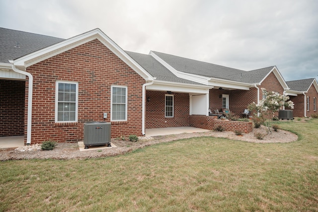 exterior space with central AC unit, a front lawn, and brick siding
