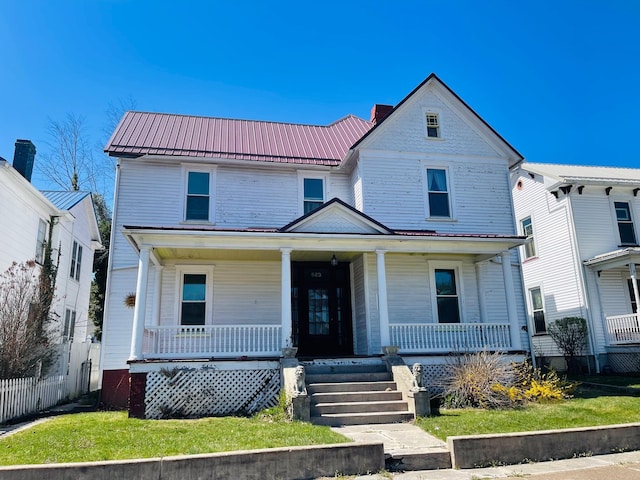 view of front of home with a porch, a standing seam roof, fence, and metal roof