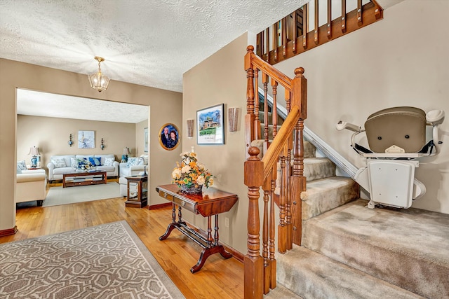 stairs with a textured ceiling, baseboards, and wood finished floors