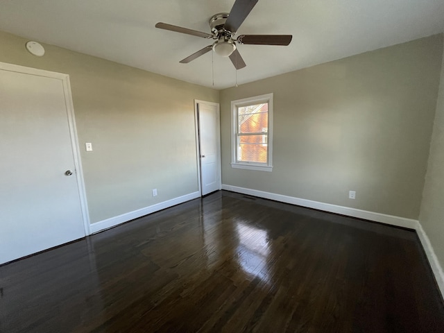 empty room with baseboards, ceiling fan, and dark wood-style flooring