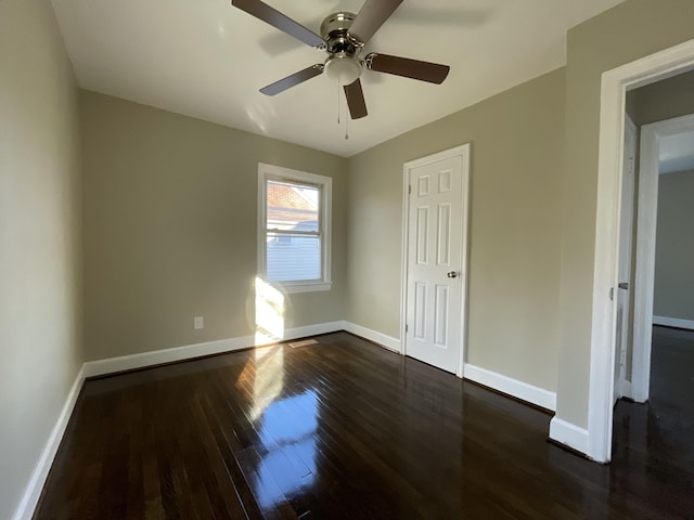 spare room with baseboards, ceiling fan, and dark wood finished floors