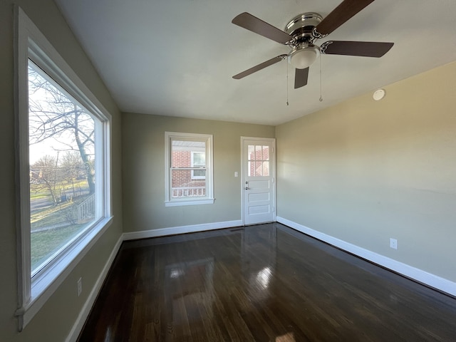 spare room featuring a ceiling fan, dark wood-type flooring, and baseboards