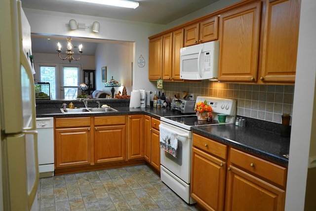 kitchen featuring an inviting chandelier, a sink, decorative backsplash, and white appliances