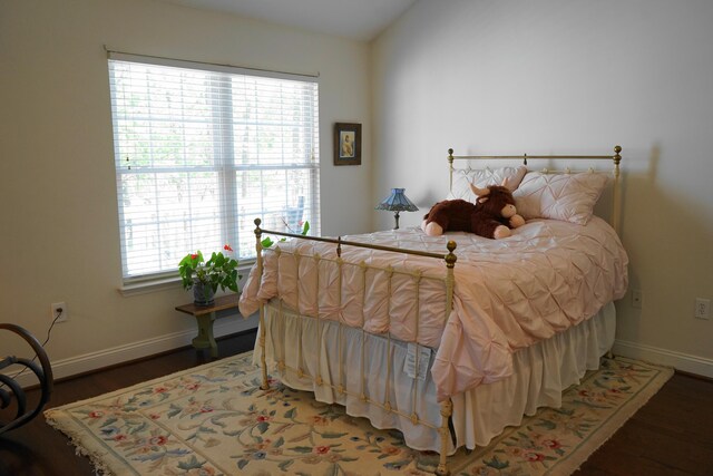 bedroom with baseboards, wood finished floors, and vaulted ceiling