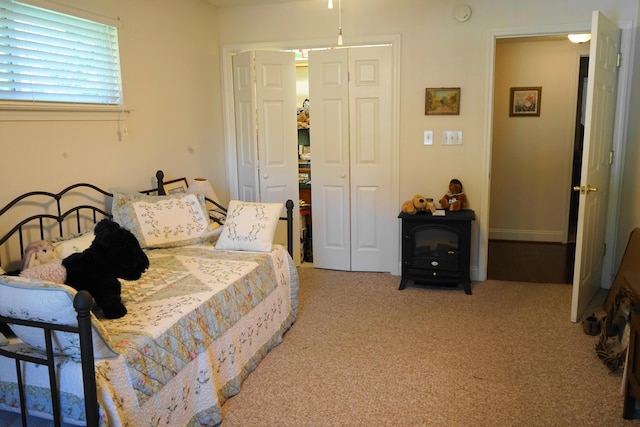 bedroom with a wood stove and light carpet