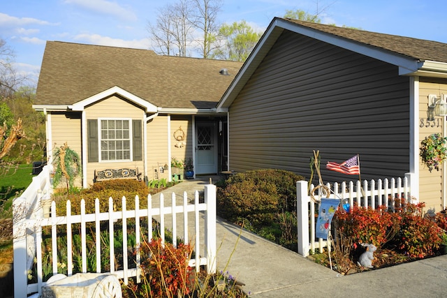 view of front of home with a fenced front yard and roof with shingles