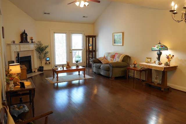 living area featuring wood finished floors, a tile fireplace, vaulted ceiling, ceiling fan with notable chandelier, and visible vents
