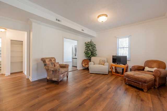 sitting room featuring visible vents, ornamental molding, baseboards, and wood finished floors