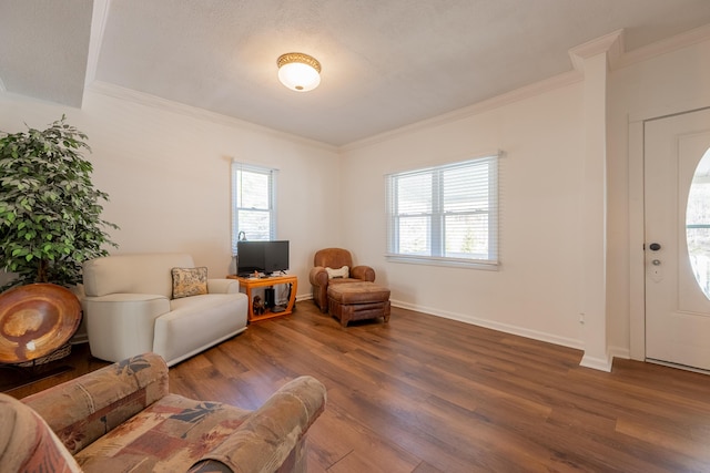 living area featuring baseboards, ornamental molding, wood finished floors, and a healthy amount of sunlight