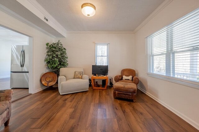 sitting room featuring baseboards, visible vents, wood finished floors, and crown molding