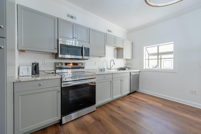 kitchen featuring a sink, appliances with stainless steel finishes, gray cabinetry, visible vents, and ornamental molding
