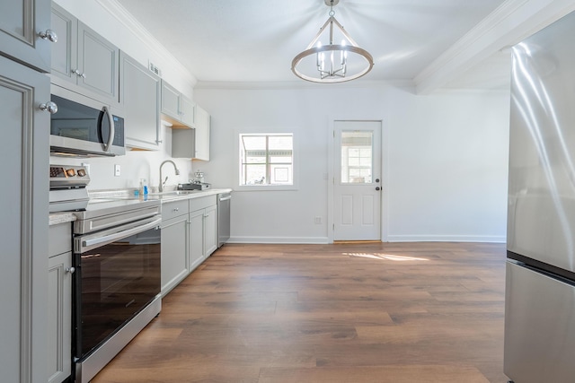 kitchen featuring a notable chandelier, a sink, appliances with stainless steel finishes, light wood-type flooring, and ornamental molding