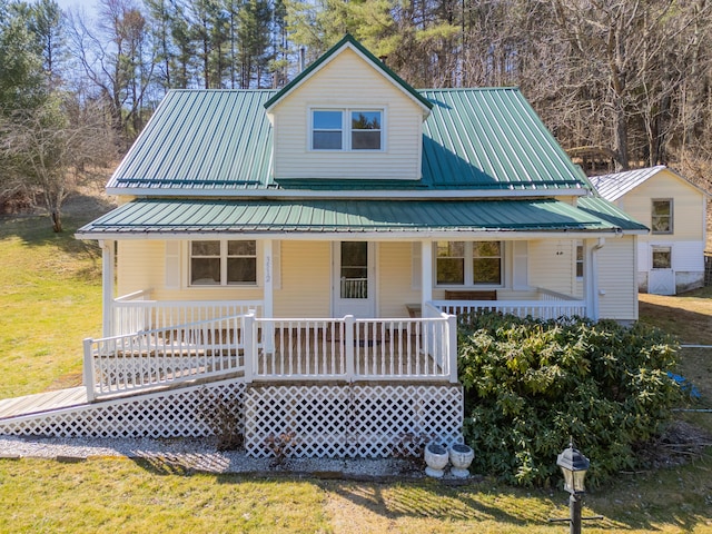 farmhouse inspired home featuring metal roof, a front yard, and covered porch