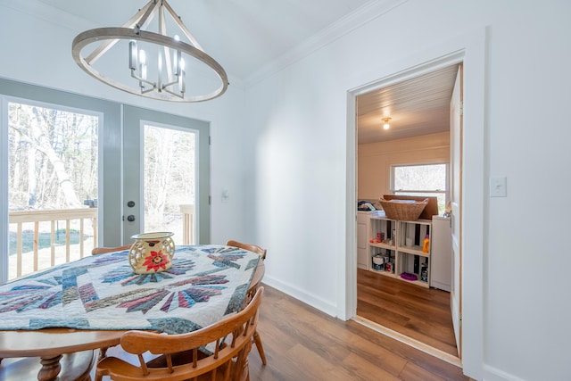 dining area featuring baseboards, a notable chandelier, wood finished floors, and ornamental molding