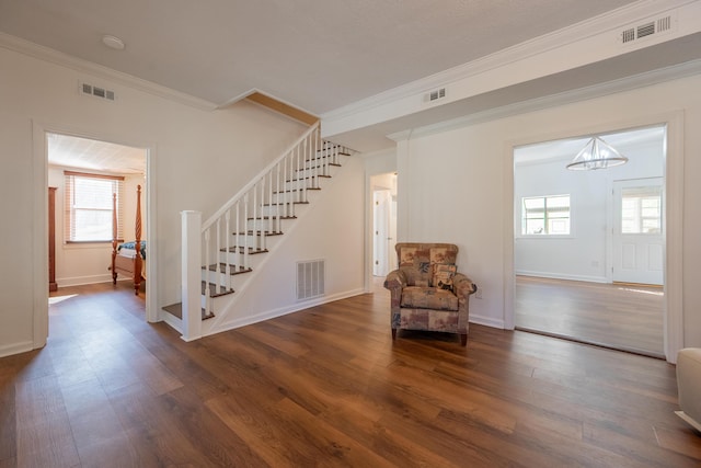 living area featuring visible vents, stairway, and wood finished floors