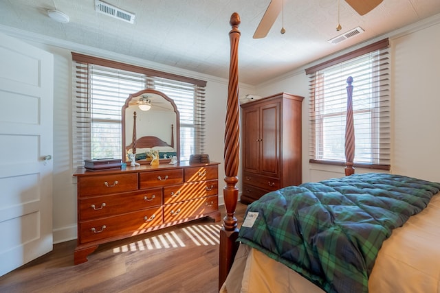 bedroom with visible vents, crown molding, and wood finished floors