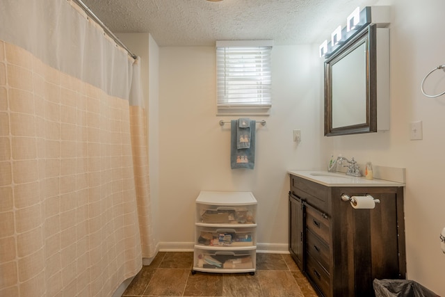 full bath with baseboards, curtained shower, a textured ceiling, and vanity