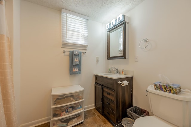 bathroom featuring toilet, curtained shower, vanity, a textured ceiling, and baseboards