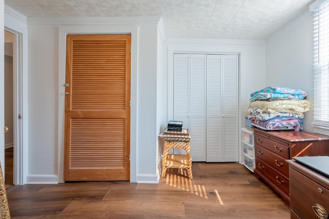 bedroom featuring baseboards, a closet, crown molding, and wood finished floors