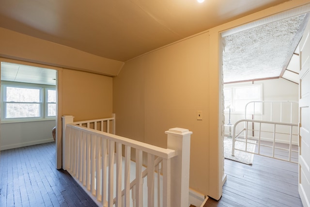 corridor featuring hardwood / wood-style floors, an upstairs landing, and vaulted ceiling