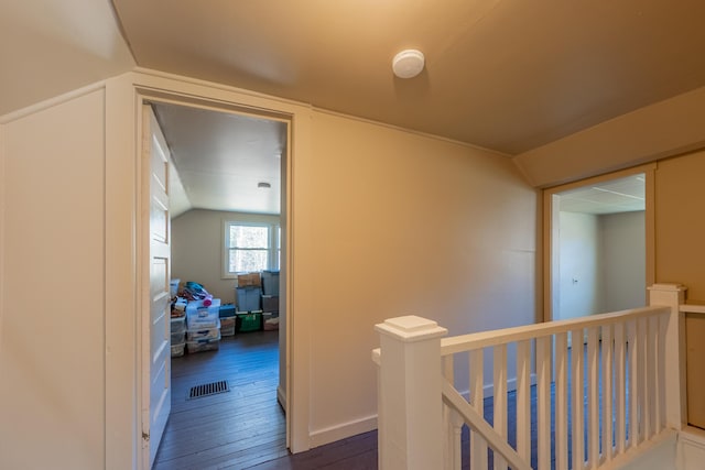 hallway with an upstairs landing, dark wood-type flooring, and lofted ceiling