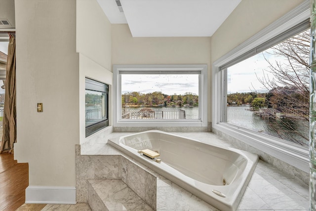 full bathroom featuring a garden tub, baseboards, visible vents, and a water view