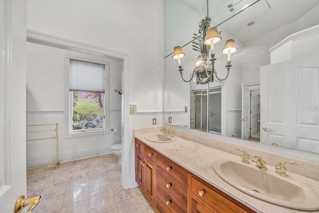 full bath featuring a sink, toilet, double vanity, and baseboards