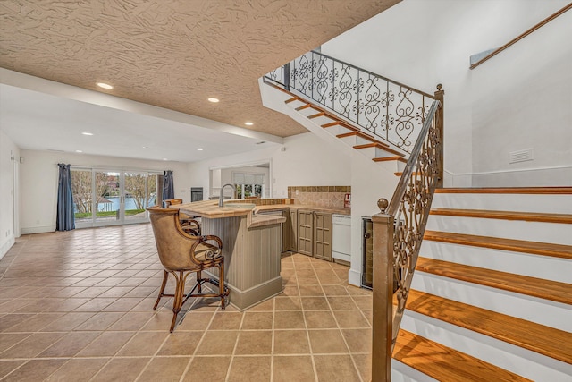 bar with recessed lighting, stairway, light tile patterned floors, dishwasher, and a sink