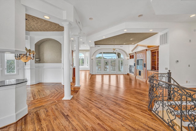 entryway with visible vents, a wealth of natural light, light wood finished floors, and decorative columns
