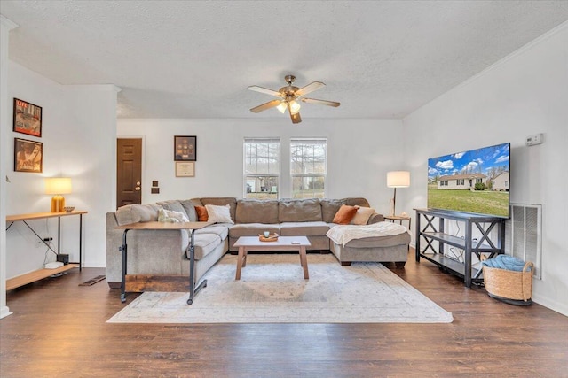 living area featuring a textured ceiling, visible vents, baseboards, ceiling fan, and wood finished floors