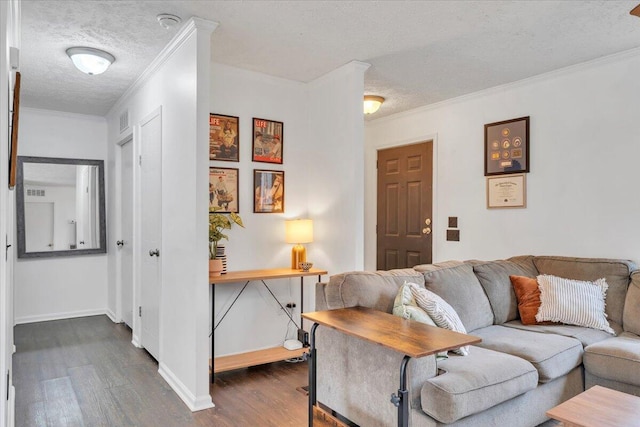 living room featuring dark wood-style flooring, a textured ceiling, visible vents, baseboards, and ornamental molding