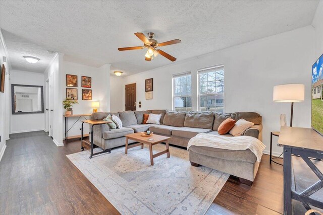 living room featuring a ceiling fan, dark wood-style floors, baseboards, and a textured ceiling