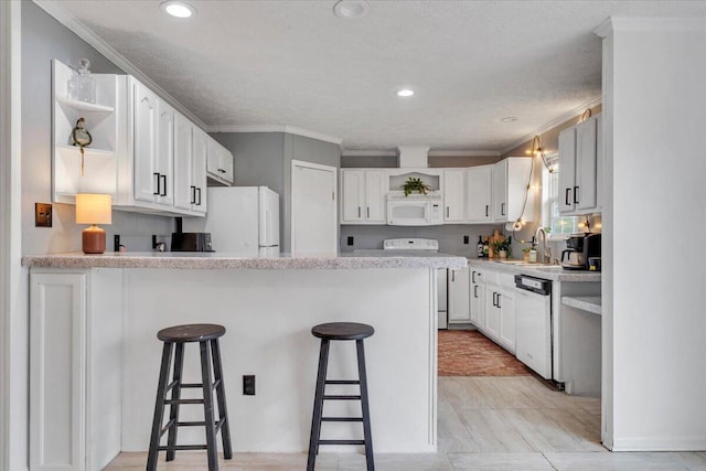 kitchen with a peninsula, white appliances, a sink, open shelves, and a kitchen breakfast bar