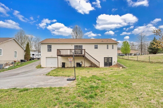 back of house featuring stairs, driveway, fence, a lawn, and a garage