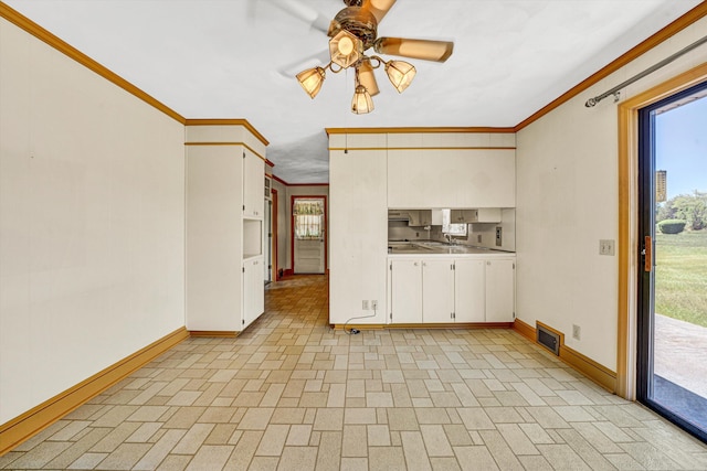 unfurnished living room with a ceiling fan, baseboards, visible vents, and ornamental molding