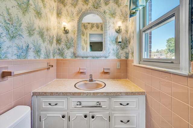 bathroom with vanity, tile walls, toilet, and wallpapered walls